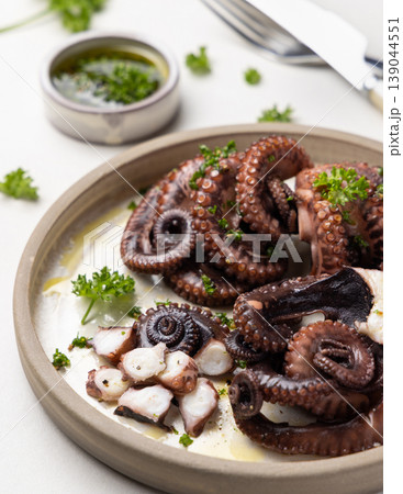 Boiled octopus on ceramic plate with olive oil and parsley dressing. Mediterranean cold appetizer 139044551