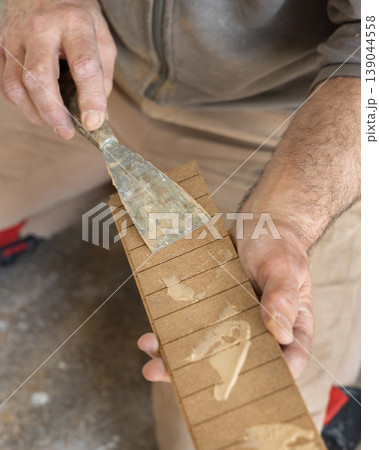 Construction worker applying adhesive on parquet planks during flooring installation in apartment Construction worker applying adhesive on parquet planks during flooring installation in apartment 139044558