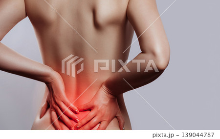 Woman having backache, pain back isolated on gray background. Scoliosis. Spinal cord problems on womans back. Beautiful naked woman touching her back. Woman having backache, pain back isolated on gray background. Scoliosis. Spinal cord problems on womans back. Beautiful naked woman touching her back. 139044787