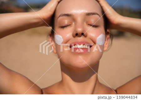 Pretty Woman With Sunscreen On Face And Hands On Head At Beach. Beauty Skincare Concept. Female Using Sun Cream Lotion Pretty Woman With Sunscreen On Face And Hands On Head At Beach. Beauty Skincare Concept. Female Using Sun Cream Lotion 139044834