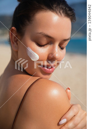 Pretty Woman With Closed Eyes And Sunscreen On Face At Beach. Beauty Skincare And Sun Protection Concept Pretty Woman With Closed Eyes And Sunscreen On Face At Beach. Beauty Skincare And Sun Protection Concept 139044842
