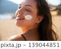 Pretty Woman With Sunscreen On Face Looking At Sunlight At Beach. Beauty Skincare Concept. Female Using Sun Cream For UV Protection 139044851