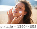 Beauty Woman Touching Face With Sunscreen On Skin At Beach. Skincare And Sun Protection Concept. Female Using Sun Cream Lotion 139044858