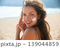 Attractive Woman Smiling And Looking At Camera With Sunscreen On Face At Beach. Beauty Skincare Concept 139044859