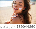 Beautiful Woman Looking Over Shoulder With Sunscreen On Face At Beach. Beauty Skincare And Sun Protection Concept 139044860