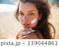 Young Woman With Sunscreen On Face And Neutral Expression At Beach. Beauty Skincare Concept. Female Using Sun Cream 139044861