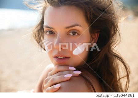 Young Woman With Sunscreen On Face And Neutral Expression At Beach. Beauty Skincare Concept. Female Using Sun Cream 139044861