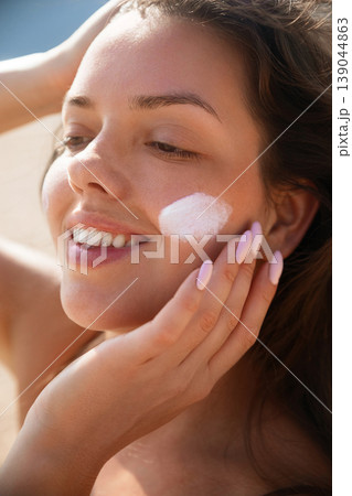 Pretty Woman Touching Cheek With Sunscreen On Face At Beach Portrait. Beauty Skincare And Sun Protection Concept 139044863