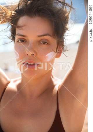 Attractive Woman With Wet Hair And Sunscreen On Face At Beach. Beauty Skincare Concept. Female Using Sun Cream Lotion 139044864