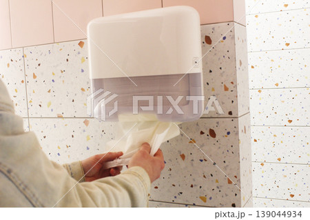 Guy wiping hands with paper towels in public toilet Guy wiping hands with paper towels in public toilet 139044934
