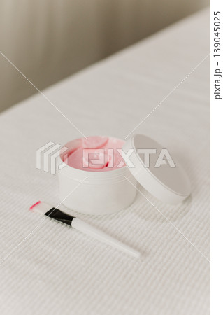 Facial pink clay mask in white jar and brush on a white background. Skin care beauty product. Cosmetology concept. 139045025