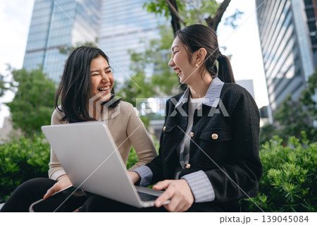 Authentic candid positive laughing two asian businesswoman enjoy talking at outdoors Authentic candid positive laughing two asian businesswoman enjoy talking at outdoors 139045084