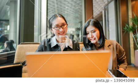 Two business asian woman talking teamwork working on laptop at indoors cafe Two business asian woman talking teamwork working on laptop at indoors cafe 139045099