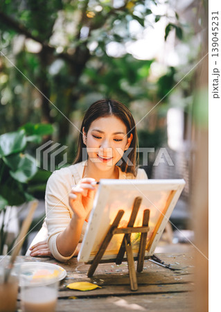 Portrait of happy young adult asian woman painting brush on canvas at workshop art lesson class. Portrait of happy young adult asian woman painting brush on canvas at workshop art lesson class. 139045231