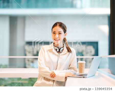 Portrait happy smiling beautiful young adult business asian woman working on laptop at indoor cafe Portrait happy smiling beautiful young adult business asian woman working on laptop at indoor cafe 139045354