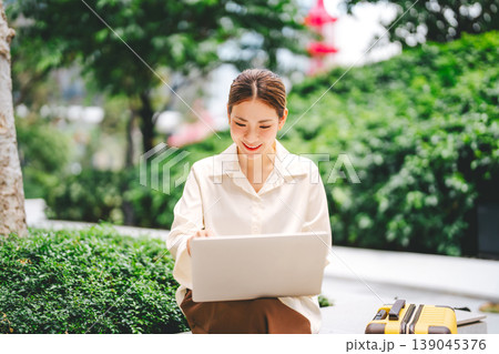 Business travel asian woman using laptop computer sitting at outdoor on day Business travel asian woman using laptop computer sitting at outdoor on day 139045376