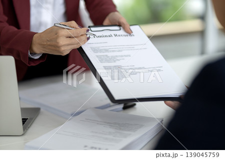 Asian adult lawyer hands pointing pen at criminal records document professional office setting for client legal consultation serious compliance review official paperwork business meeting Asian adult lawyer hands pointing pen at criminal records document professional office setting for client legal consultation serious compliance review official paperwork business meeting 139045759