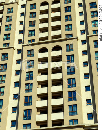 View of a tall building with multiple balconies and many windows under a clear sky during daylight in an urban area 139045806
