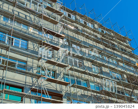 Building renovation project takes place in urban area with scaffolding set up for workers to access higher levels of the structure Building renovation project takes place in urban area with scaffolding set up for workers to access higher levels of the structure 139045824