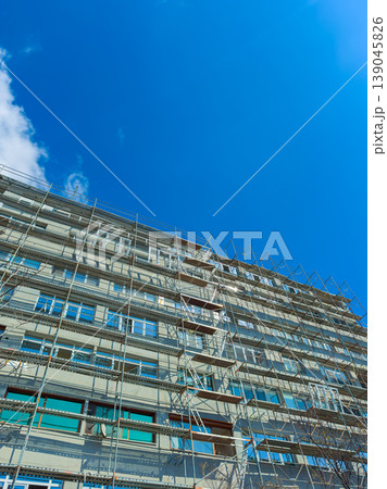 Building renovation with scaffolding under a clear blue sky in a city setting during daytime hours Building renovation with scaffolding under a clear blue sky in a city setting during daytime hours 139045826