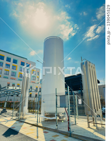 Large storage tank is positioned outside of a building in a city during a sunny day with clear blue sky and scattered clouds Large storage tank is positioned outside of a building in a city during a sunny day with clear blue sky and scattered clouds 139045829