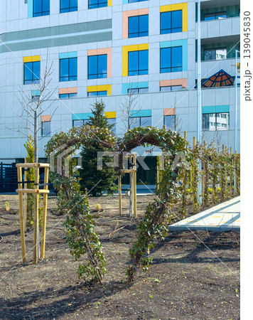 Heart-shaped plant formation in front of a modern building with colorful windows during daytime 139045830