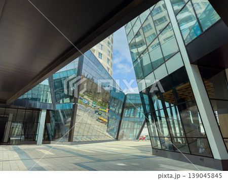 Modern building design shows reflection of the surroundings in the glass walls during daytime in an urban area Modern building design shows reflection of the surroundings in the glass walls during daytime in an urban area 139045845