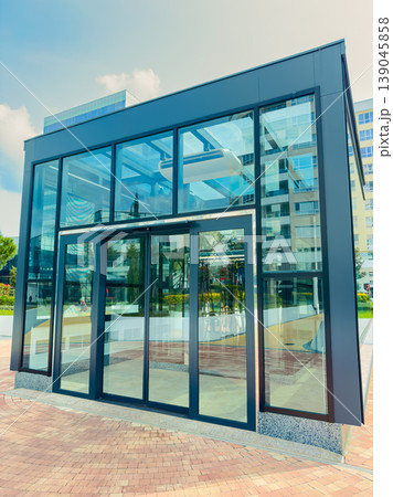 Modern glass building located in a city area showcases a sleek design with large windows in bright daylight surrounded by urban greenery Modern glass building located in a city area showcases a sleek design with large windows in bright daylight surrounded by urban greenery 139045858