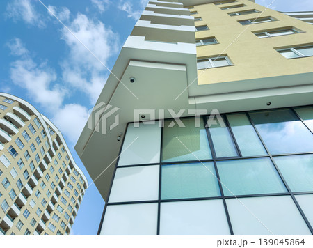 Modern buildings reach toward the blue sky in a city area with clouds in the background during the daytime 139045864
