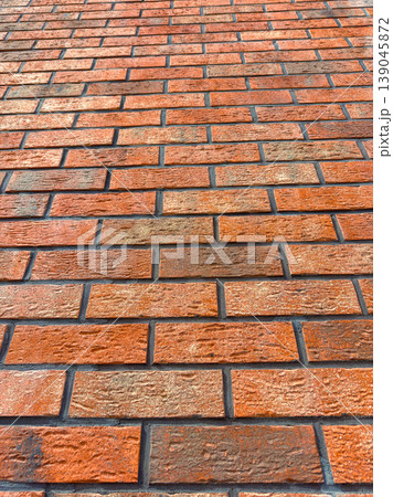 Brick wall with different shades of orange and brown, laid out in a neat pattern, creating a solid structure in a construction or renovation setting during daytime hours Brick wall with different shades of orange and brown, laid out in a neat pattern, creating a solid structure in a construction or renovation setting during daytime hours 139045872