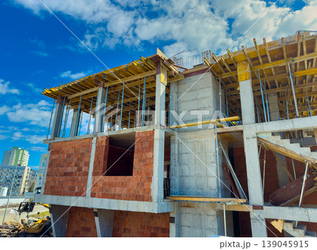 New building construction takes place under bright blue sky with clouds in urban area in early afternoon New building construction takes place under bright blue sky with clouds in urban area in early afternoon 139045915