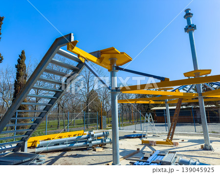 Construction site shows metal framework and stairs for a new structure in a park under a clear blue sky in the afternoon Construction site shows metal framework and stairs for a new structure in a park under a clear blue sky in the afternoon 139045925