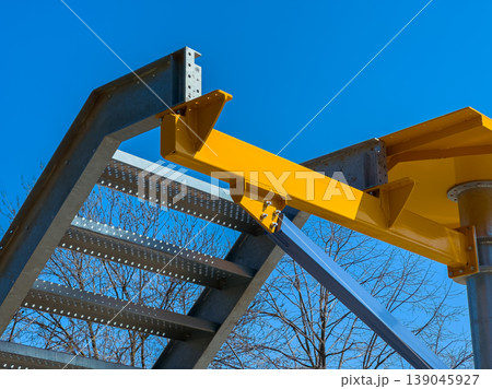 Construction site shows metal structure with yellow support beam on steel staircase under clear blue sky in daytime Construction site shows metal structure with yellow support beam on steel staircase under clear blue sky in daytime 139045927