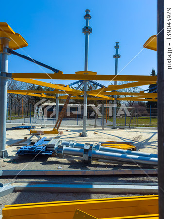 Construction of a new playground structure in a park during a sunny day in spring with equipment and materials arranged for assembly Construction of a new playground structure in a park during a sunny day in spring with equipment and materials arranged for assembly 139045929