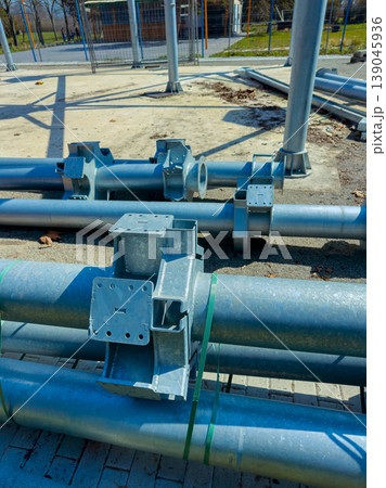 Construction site shows metal pipes and connectors laid out on the ground with a clear blue sky in the background during a sunny day Construction site shows metal pipes and connectors laid out on the ground with a clear blue sky in the background during a sunny day 139045936