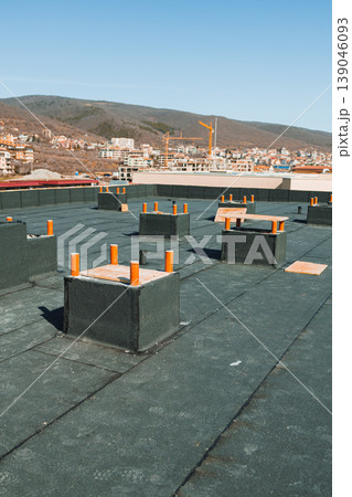Construction site on a rooftop with orange markers and a view of the city under a clear blue sky in the afternoon 139046093