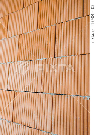 Construction workers build a wall using red bricks in a residential area during daylight hours in the summer season 139046103