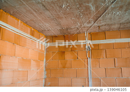 Construction site showing brick wall and electrical wiring installation in a building Construction site showing brick wall and electrical wiring installation in a building 139046105