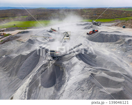 Granite quarry operation shows heavy machinery working on rock processing and material handling during daylight hours Granite quarry operation shows heavy machinery working on rock processing and material handling during daylight hours 139046121