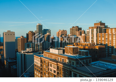 City skyline view from a rooftop during sunset showing tall buildings and a clear sky in an urban area with some shadows on structures City skyline view from a rooftop during sunset showing tall buildings and a clear sky in an urban area with some shadows on structures 139046129