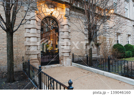 Entrance to a building in a city with plants visible inside during evening hours 139046160