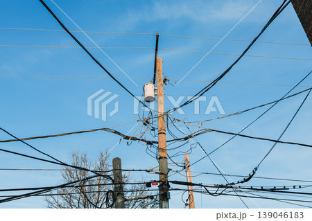 Utility pole with wires against the sky in an urban area during the day with trees nearby and power cables connected Utility pole with wires against the sky in an urban area during the day with trees nearby and power cables connected 139046183