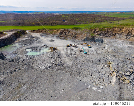 Granite quarry site with machinery and raw materials in a rural landscape during daytime 139046215