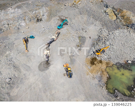Machinery working at a granite quarry site in daytime near a water pool Machinery working at a granite quarry site in daytime near a water pool 139046225