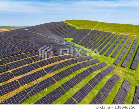 Solar panels cover a hillside in a renewable energy site during bright daylight, showcasing sustainable technology and environmental efforts for power generation 139046256