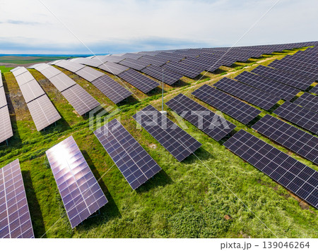 Rows of solar panels cover green land in a renewable energy field at midday in an open landscape 139046264