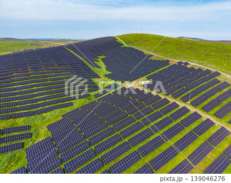 Solar panels cover a large area of land on a sunny day in a renewable energy facility located in a green valley Solar panels cover a large area of land on a sunny day in a renewable energy facility located in a green valley 139046276