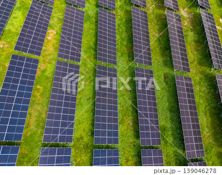 Large solar panel farm located in an open field during daylight hours showcasing rows of solar panels on grassy land 139046278