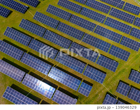Solar panels are arranged in rows on open land for energy production during the day in a sunny location 139046329