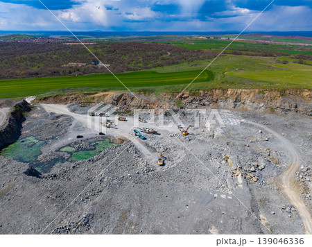 Granite quarry site showing heavy machinery and green water bodies with grassland in the background Granite quarry site showing heavy machinery and green water bodies with grassland in the background 139046336